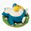 Figura coleccionable Relaxing Time de Snorlax y Pikachu de Pokémon, Pikachu dormido boca abajo sobre la panza de Snorlax, base redonda con hierba verde y flores moradas